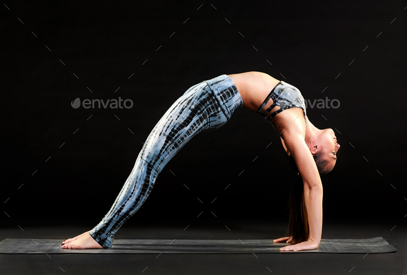 Woman demonstrating a straight legged wheel pose Stock Photo by Photology75