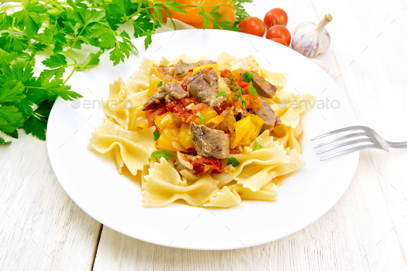 Farfalle with turkey and vegetables in sauce on table Stock Photo by rezkrr