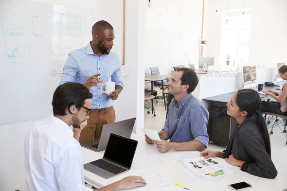 Young black man presenting an office meeting at a whiteboard Stock Photo by monkeybusiness