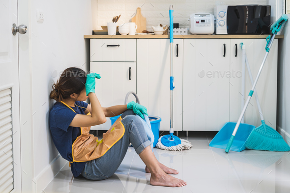 Tired young woman sitting on kitchen floor Stock Photo by kitzstocker