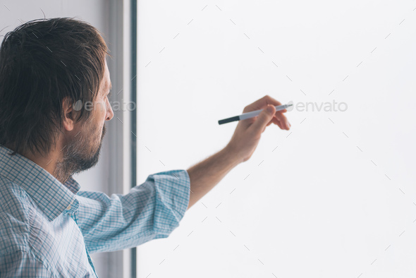 Businessman in office writing on whiteboard Stock Photo by stevanovicigor