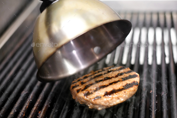 Cooking a beef hamburger patty on a grill Stock Photo by Photology75