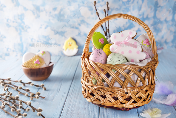 Easter cookies, bunnies and Multicolored Easter eggs in a basket on light blue background Stock Photo by lyulkamazur