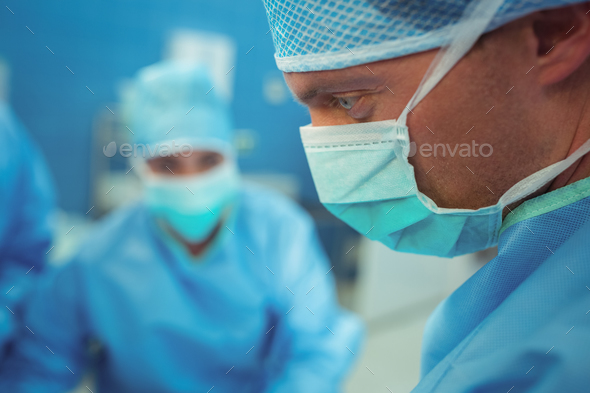 Male surgeon wearing surgical mask in operation theater Stock Photo by Wavebreakmedia