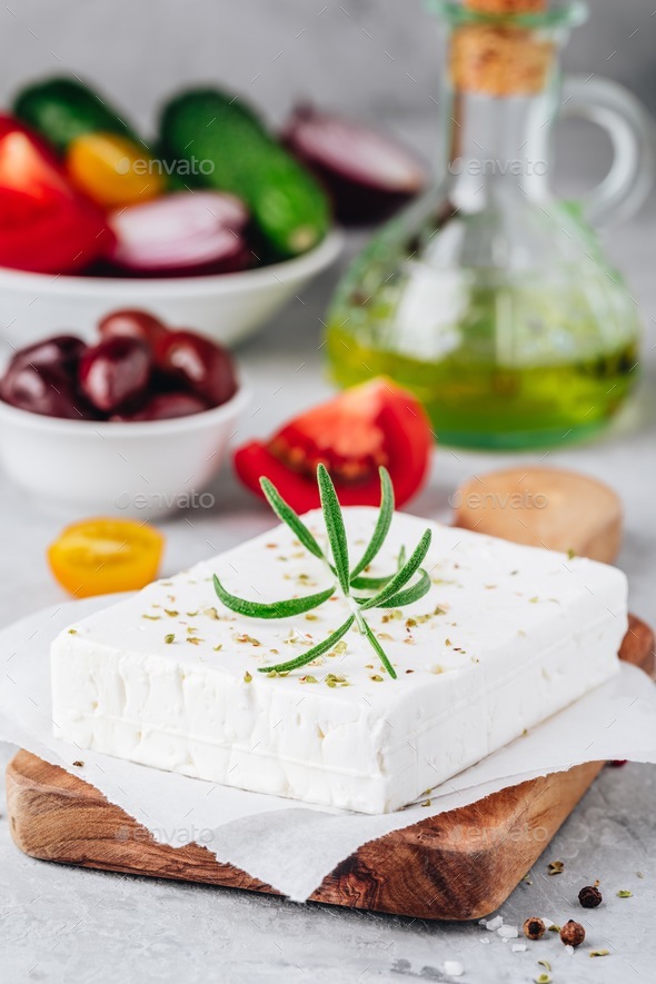 Homemade greek cheese feta with rosemary on wooden cutting board. Ingredients for greek salad Stock Photo by nblxer