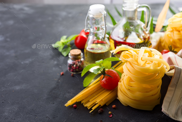 Fettuccine and spaghetti with ingredients for cooking pasta on black stone slate background Stock Photo by lyulkamazur