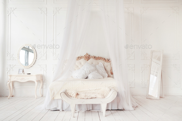 bedroom in soft light colors. big comfortable double bed in elegant classic bedroom Stock Photo by Vladdeep