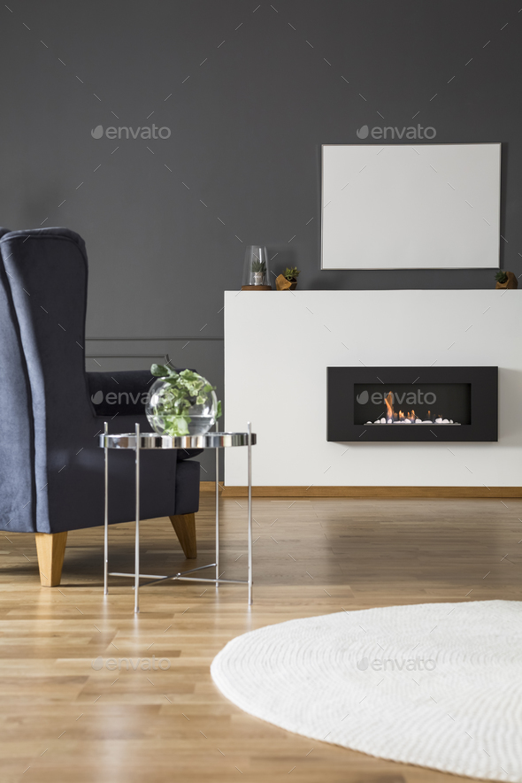 Real photo of a comfy armchair standing in front of a bio firepl Stock Photo by bialasiewicz