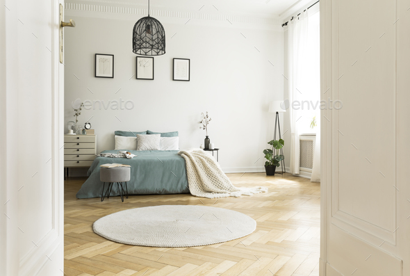 White round rug in spacious bedroom interior with green bed unde Stock Photo by bialasiewicz