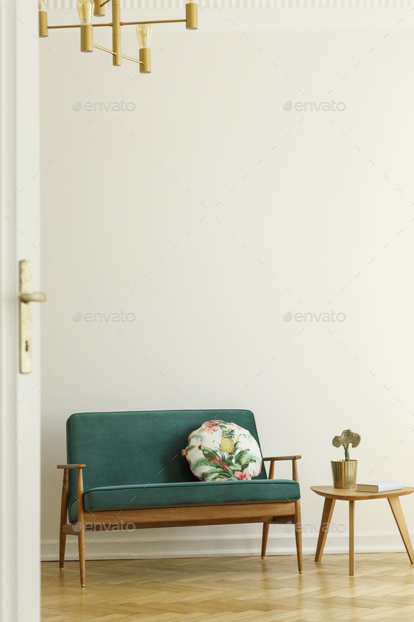 Floral pattern pillow on a retro style, green sofa and a wooden Stock Photo by bialasiewicz