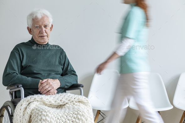 Sad paralyzed elderly man in the wheelchair in the nursing house Stock Photo by bialasiewicz