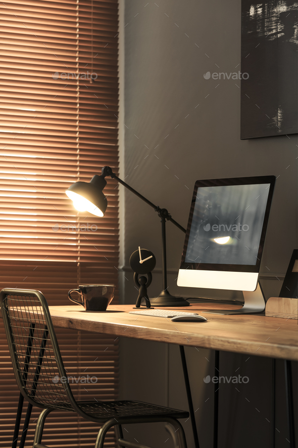 Lamp and desktop computer on desk in dark freelancer\'s room inte Stock Photo by bialasiewicz
