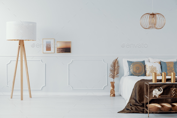 Light grey bedroom interior with gold accents in real photo with Stock Photo by bialasiewicz