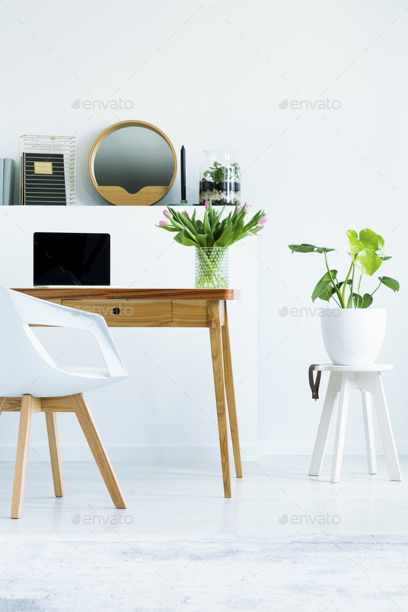 Plant on stool next to wooden desk with laptop in white home off Stock Photo by bialasiewicz