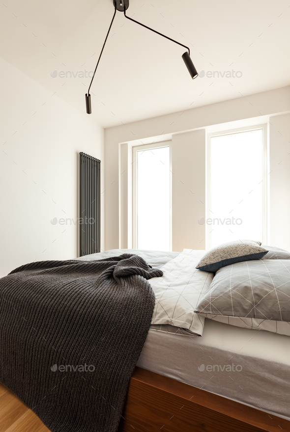 Side angle of a double bed with blanket and pillows, big window Stock Photo by bialasiewicz