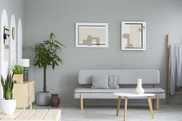 Wooden table in front of grey sofa in simple living room interio Stock Photo by bialasiewicz