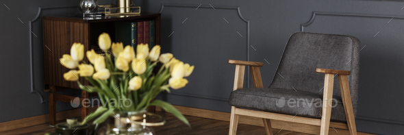 A modern gray armchair in a dark living room interior with woode Stock Photo by bialasiewicz