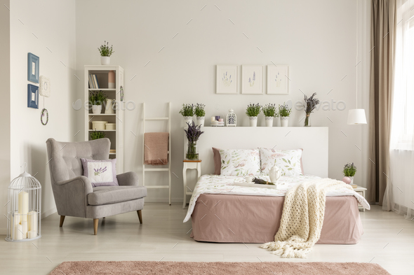 Real photo of a feminine bedroom interior with a comfy armchair, Stock Photo by bialasiewicz