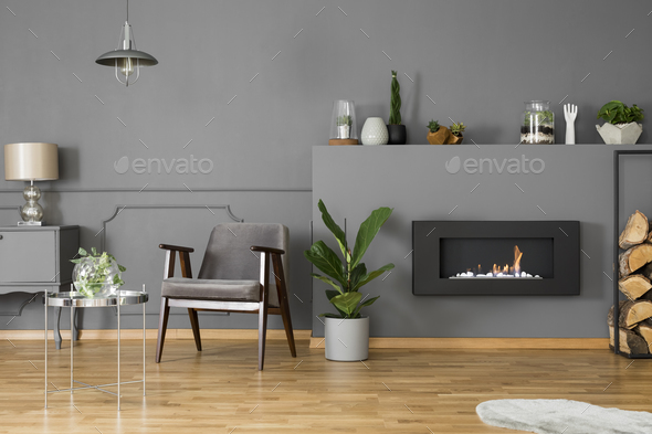 Black fireplace between plant and firewood in grey living room i Stock Photo by bialasiewicz