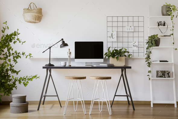Stools at desk with lamp and desktop computer in freelancer\'s in Stock Photo by bialasiewicz