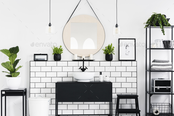 Mirror and poster above black washbasin in bathroom interior wit Stock Photo by bialasiewicz