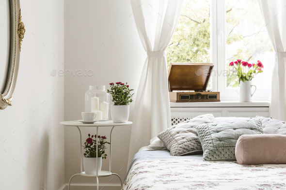 White bedroom interior in real photo with bedside table with tea Stock Photo by bialasiewicz