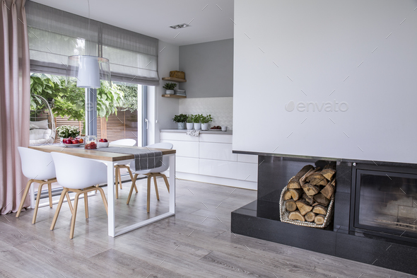 Modern fireplace and wood in a spacious dining room interior wit Stock Photo by bialasiewicz