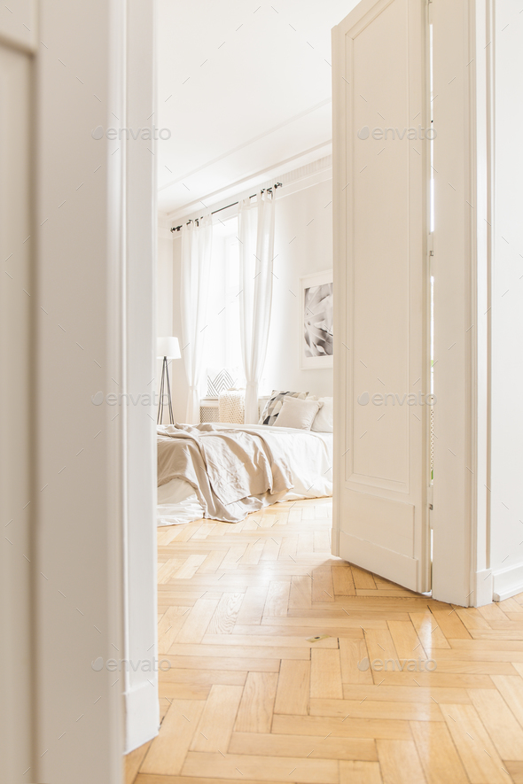 View through tall, open white door on a stylish, bright bedroom Stock Photo by bialasiewicz