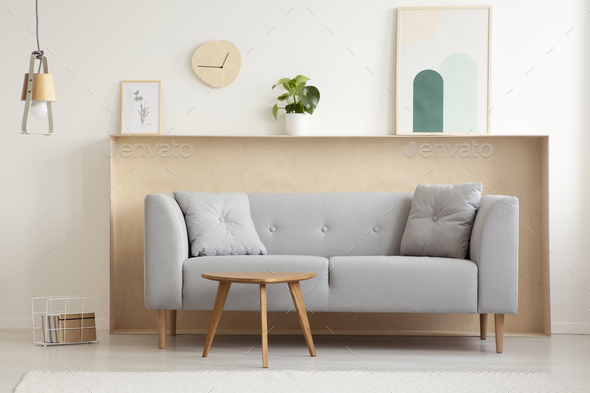 Wooden table in front of grey sofa in simple living room interio Stock Photo by bialasiewicz