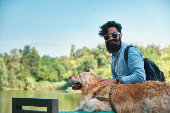 Young man sitting with his dog on the chair in the park hugging Stock Photo by arthurhidden
