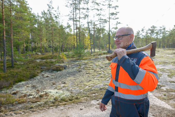 Mature Happy Caucasian Man Holding Axe Harvesting Timber In The Forest