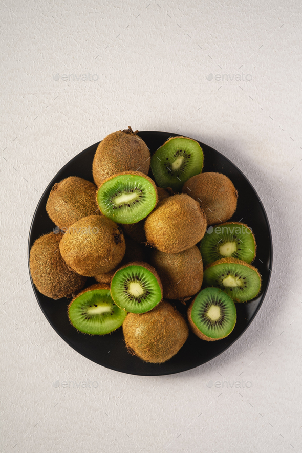 Kiwi Fruits Half Sliced In Black Plate On Vibrant Plain White