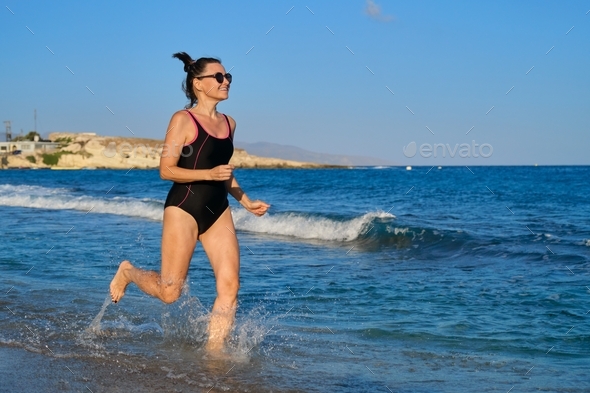 Happy Mature Woman Running Along The Beach Copy Space Stock Photo By