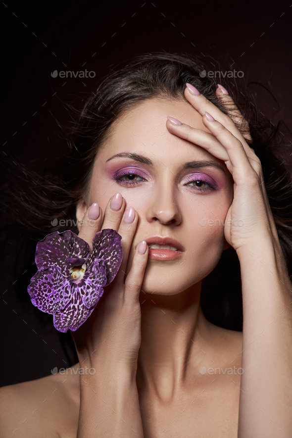 Beauty Portrait Of A Nude Woman With A Purple Flower In Her Hands On A