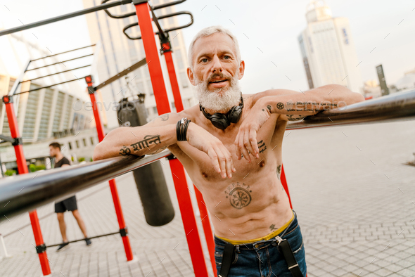 Shirtless Mature Man With Tattoo Working Out On Sports Ground Stock