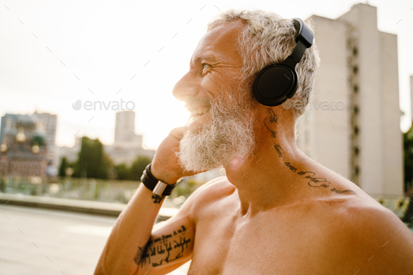 Shirtless Mature Man Listening Music With Headphones Outdoors Stock