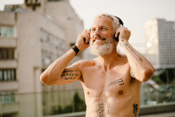 Shirtless Mature Man Listening Music With Headphones Outdoors Stock