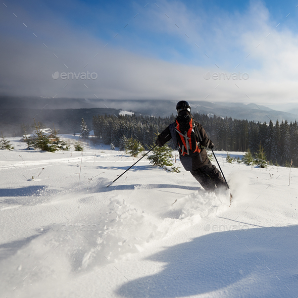 Male Skier Freeriding On Wide Open Mountain Slope Skiing Down Between