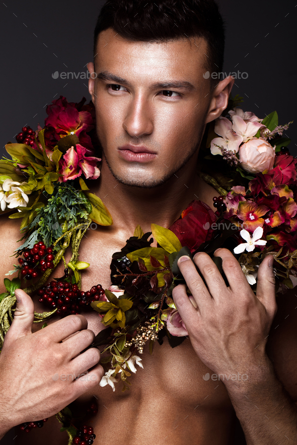 A Handsome Man With A Naked Torso Bronze Tan And Flowers On His Body