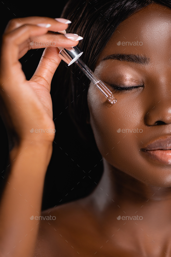 Portrait Of African American Naked Woman Applying Serum On Face