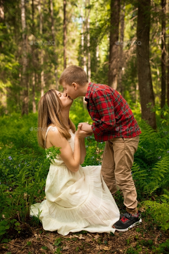 Mom With Her Son In The Woods A Woman Kneels And Kisses Her Son Stock