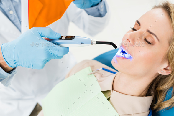 Dentist Using Uv Lamp To Treat Patient Teeth In Modern Dental Clinic