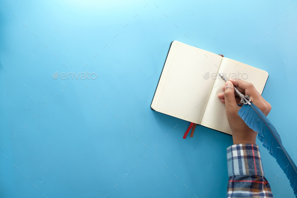 Man Hand Writing With Fountain Pen On Notepad On Blue Background Stock