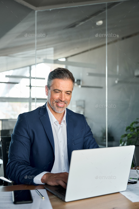 Happy Middle Aged Business Man Ceo Wearing Suit Sitting In Office Using