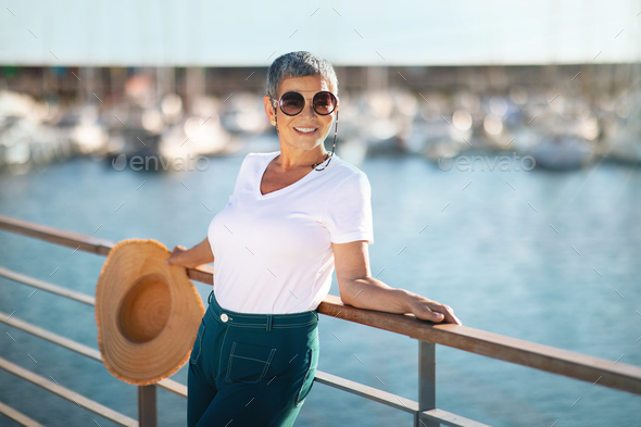 Cheerful Mature Lady Posing Standing At Pier Enjoying Golden Holidays