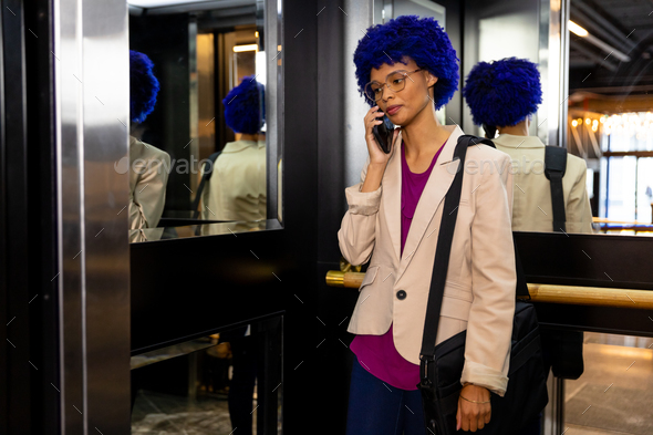 Happy Biracial Casual Businesswoman With Blue Afro Talking On