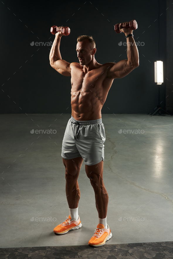 Caucasian Athlete In Full Growth Trains With Dumbbells Raises His Arms