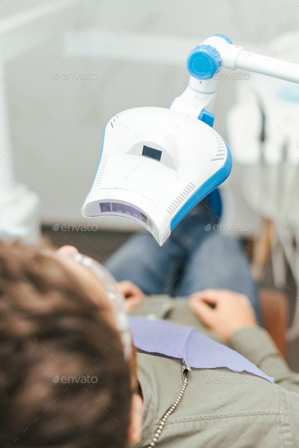 Patient Laying Under The UV Lamp During The Whitening Procedure Stock