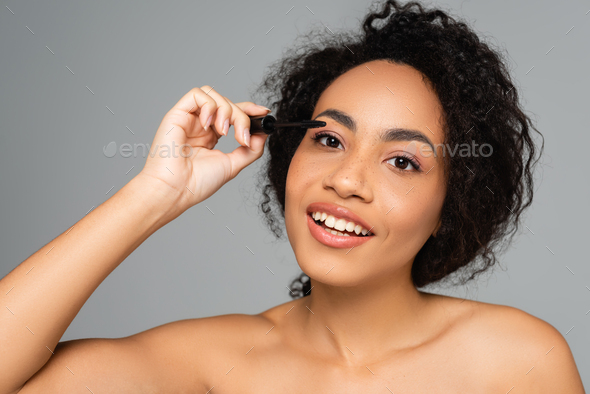 Smiling African American Woman With Naked Shoulders Applying Mascara