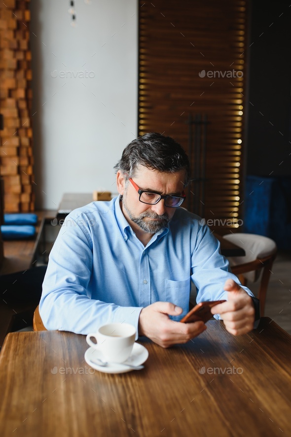 Confident Mature Man In Formalwear Drinking Coffee And Typing A Message